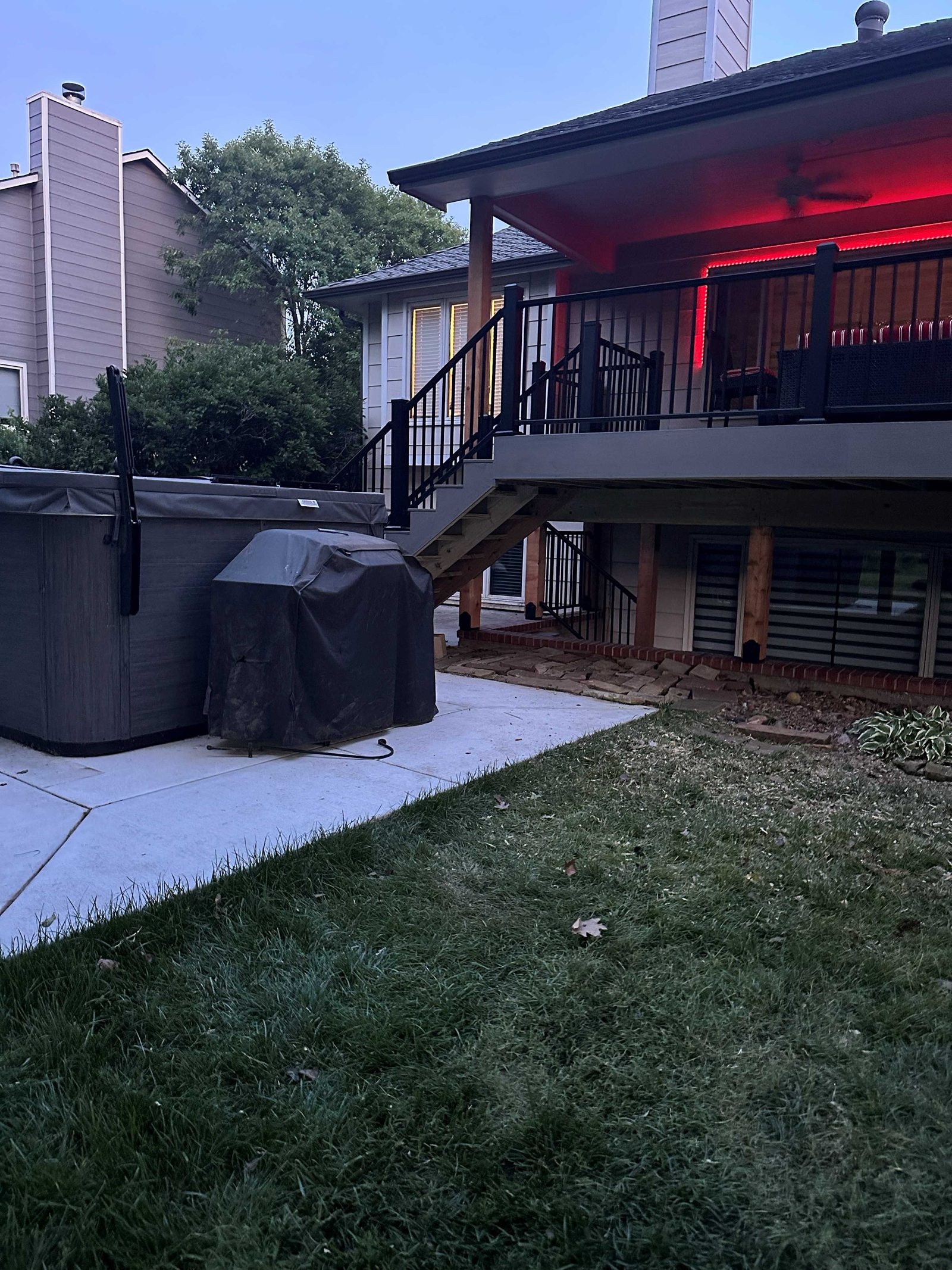 Finished gray composite deck and stairs with black railing at dusk