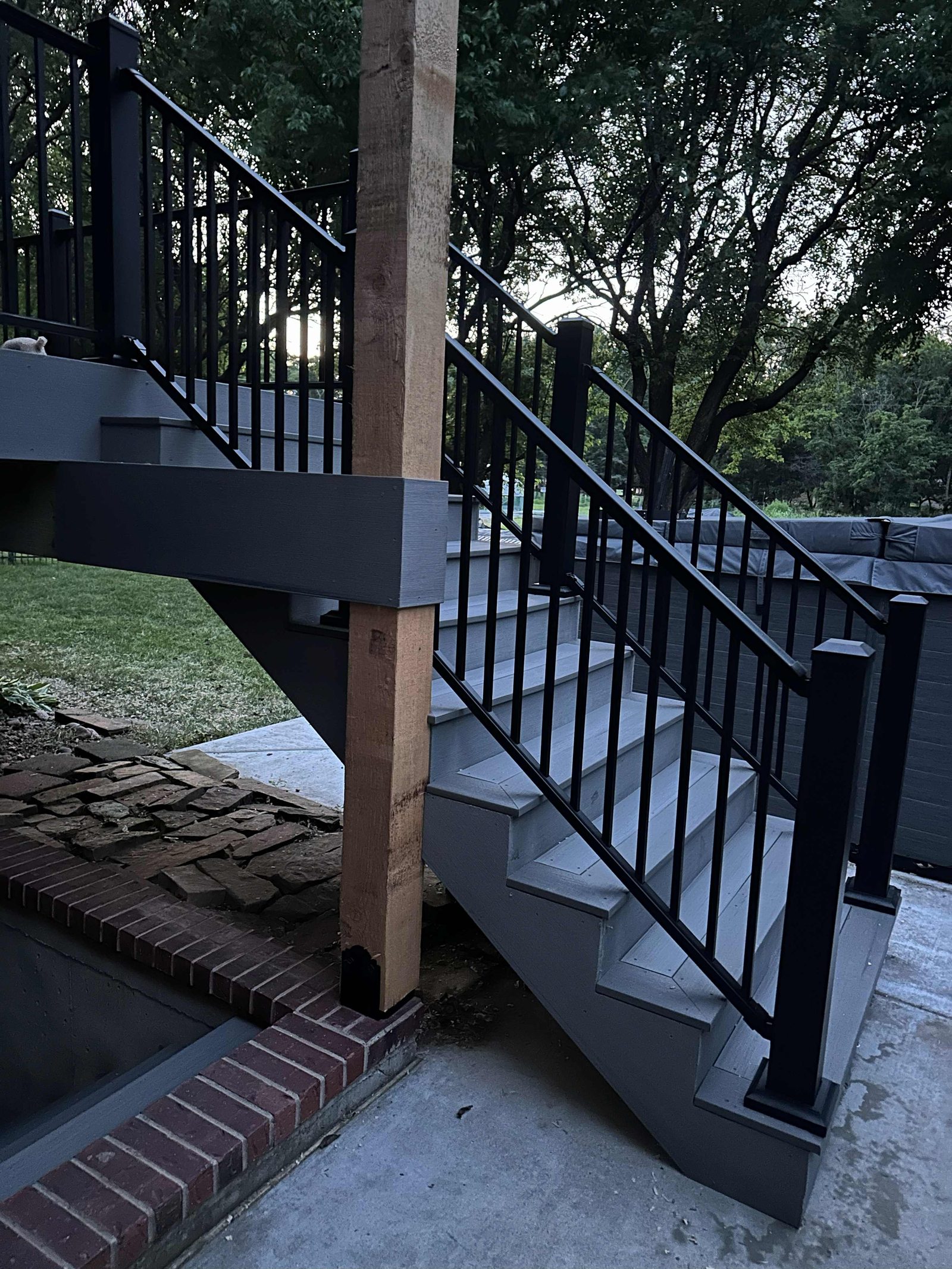 Composite stairs with black railing and rough-sawn post on a steel base